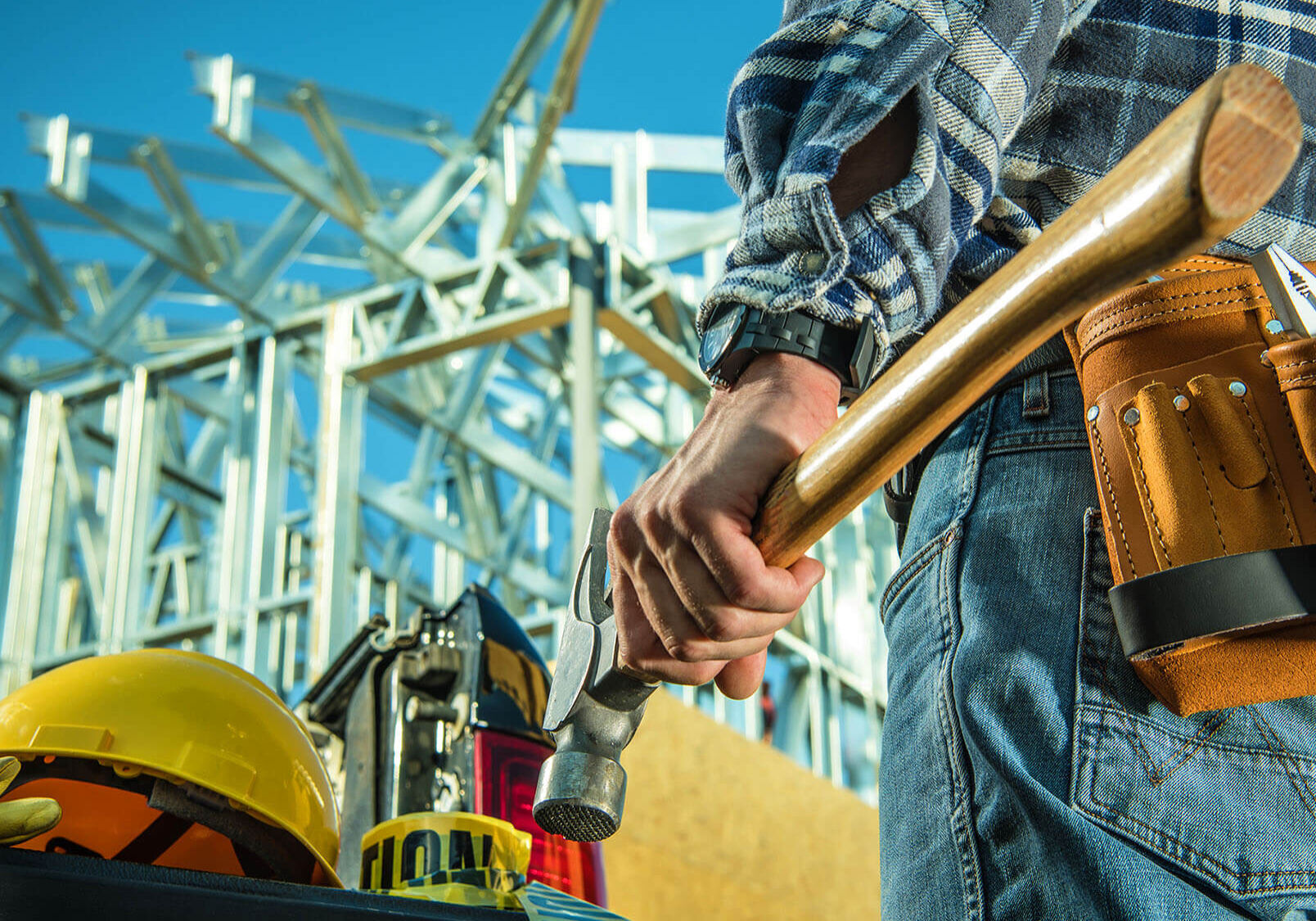 Caucasian Steel Construction Worker with Large Professional Hammer in Front of Construction Site.